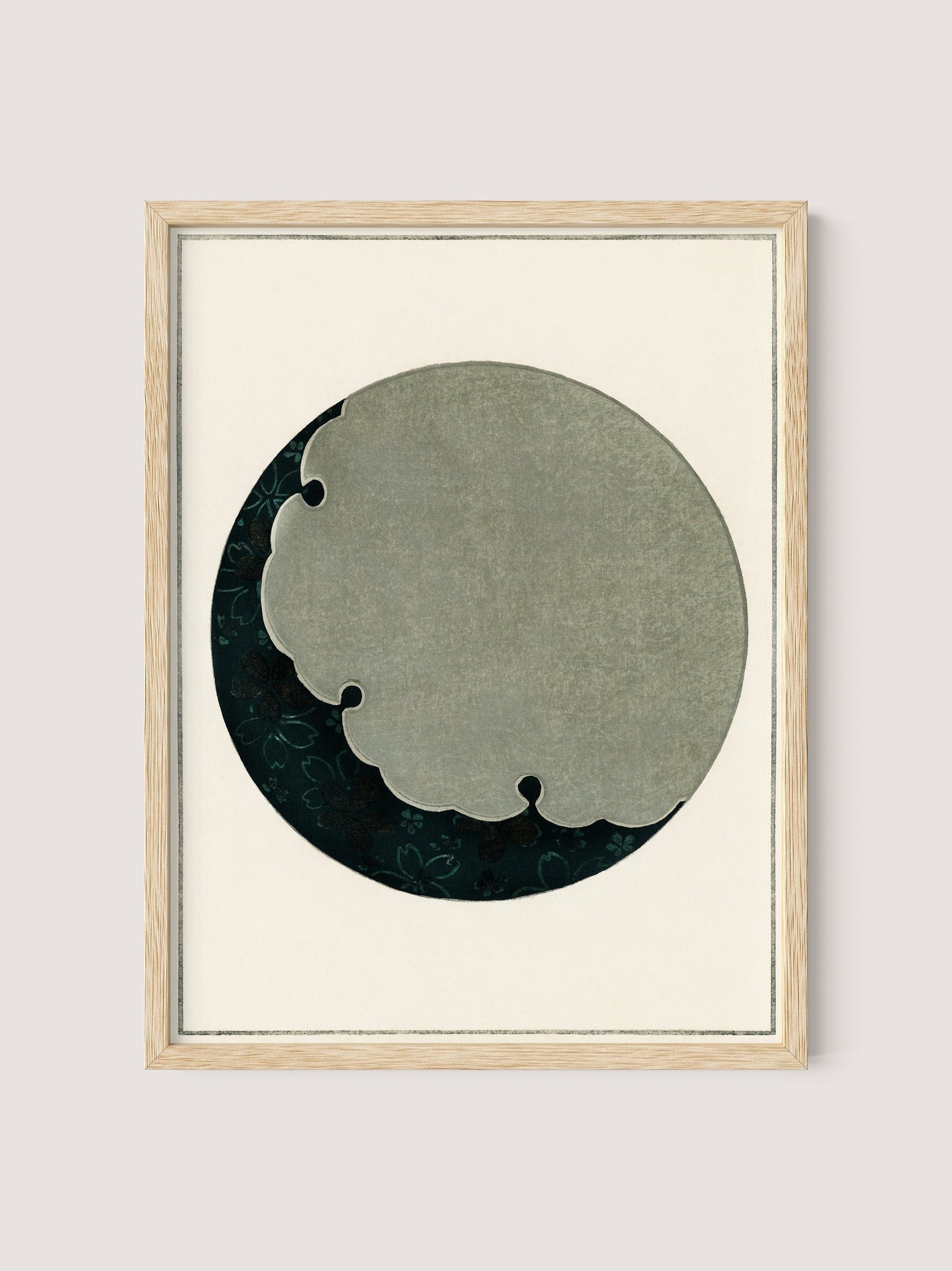 Introducing "Moon" – a framed artwork featuring an abstract circular design reminiscent of Japanese aesthetics. The circle has a textured, cloudy grey section on the top right, blending into a dark green and black background with subtle floral patterns. The natural oak frame contrasts beautifully with the simple, light beige background.