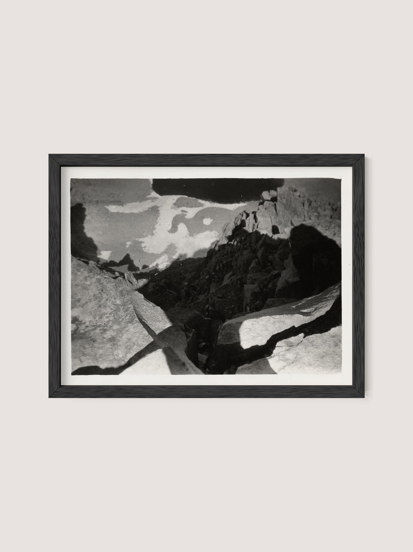 A black and white photograph titled "Looking Down From Mt. Whitney," framed in black oak, depicts a rocky landscape with jagged formations casting shadows. The dramatic interplay of light and dark in this Louis Fleckenstein photo creates an abstract, rugged appearance, evoking a sense of depth and texture in a natural setting.