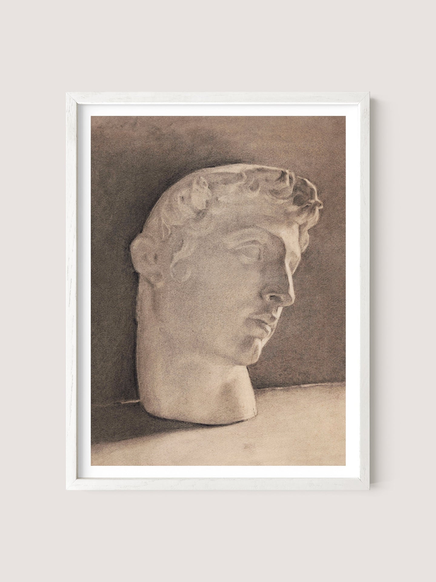 Introducing "Study of a Plaster Head," a framed monochrome sketch featuring the head of a classical sculpture of a young man with curly hair in a slightly downward-facing profile view. Set against a neutral background and framed in sleek White Oak, this neoclassical piece exudes minimalist elegance, capturing timeless beauty with simplicity and grace.