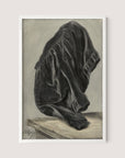 The framed artwork titled "Drape Study" features a detailed depiction of a crumpled black garment carefully draped over an unseen object. The intricate folds and shadows create a highly realistic texture, beautifully capturing the interplay of light and darkness. Set against a neutral gray background, the monochrome study is further emphasized. The artist's signature can be found in the bottom left corner. This piece comes in an elegant White Oak frame.