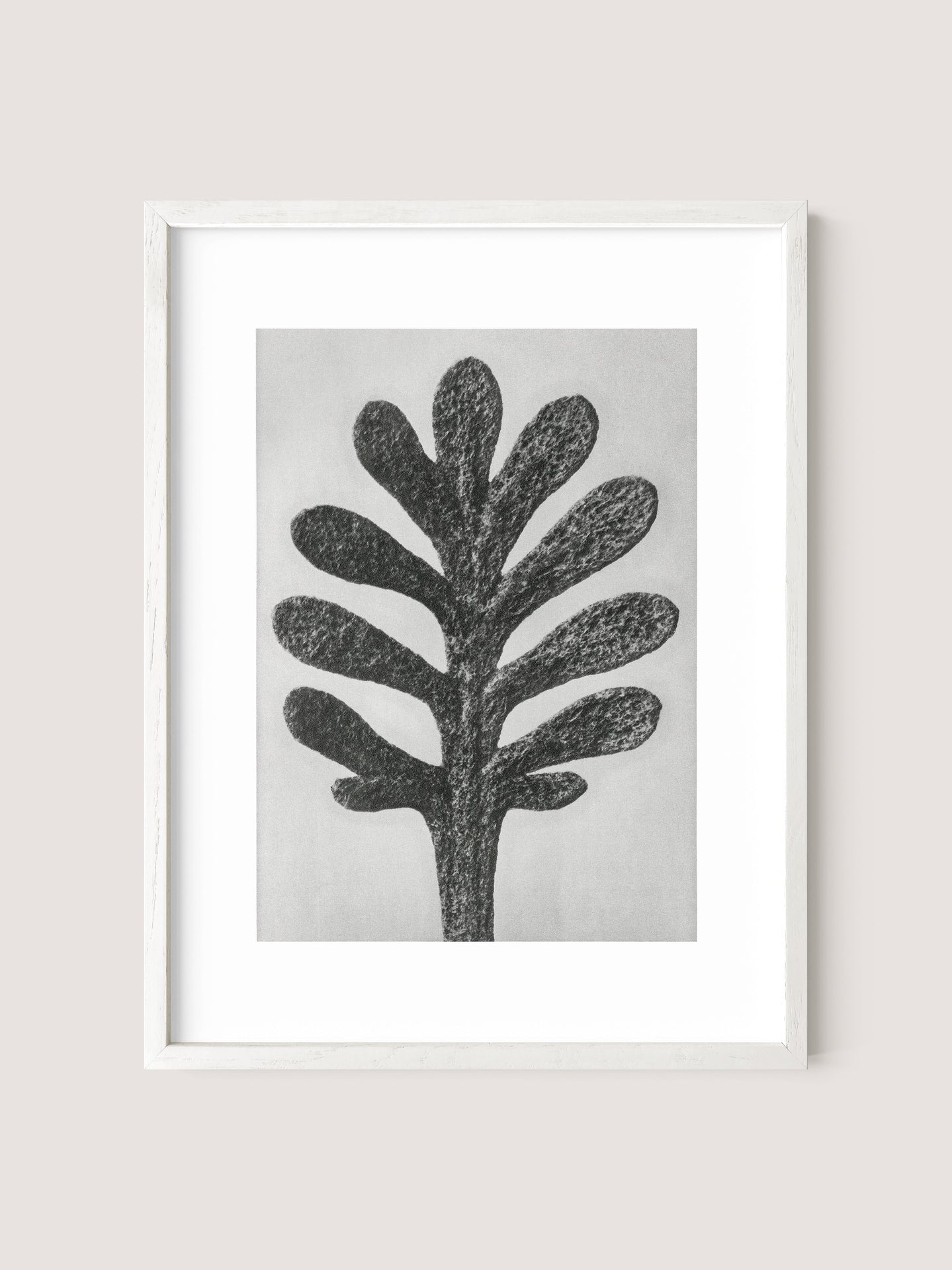 The Yarrow Leaf framed artwork features a black and gray abstract depiction of a tree with multiple branches resembling thick, rounded leaves, displayed against a light gray background. This painterly print captures botanical beauty in a simple White Oak frame.