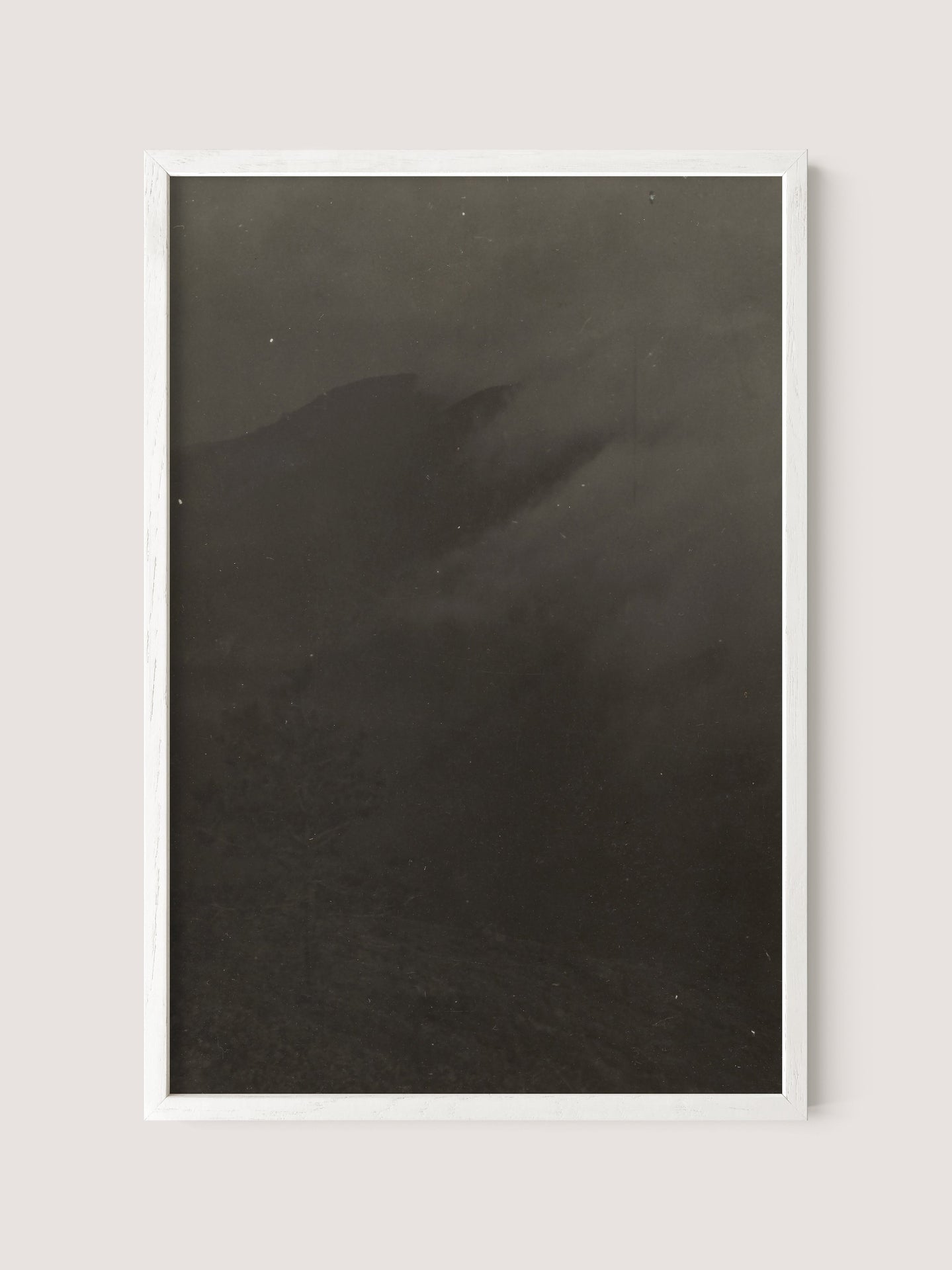 The "Mountain Landscape" piece features a framed black and white print with a white oak border, capturing a dark, misty landscape or mountain scene. The image is predominantly dark, with faint outlines of hills or mountains barely visible through the dense fog, reminiscent of works by the 19th Century American photographer Louis Fleckenstein.