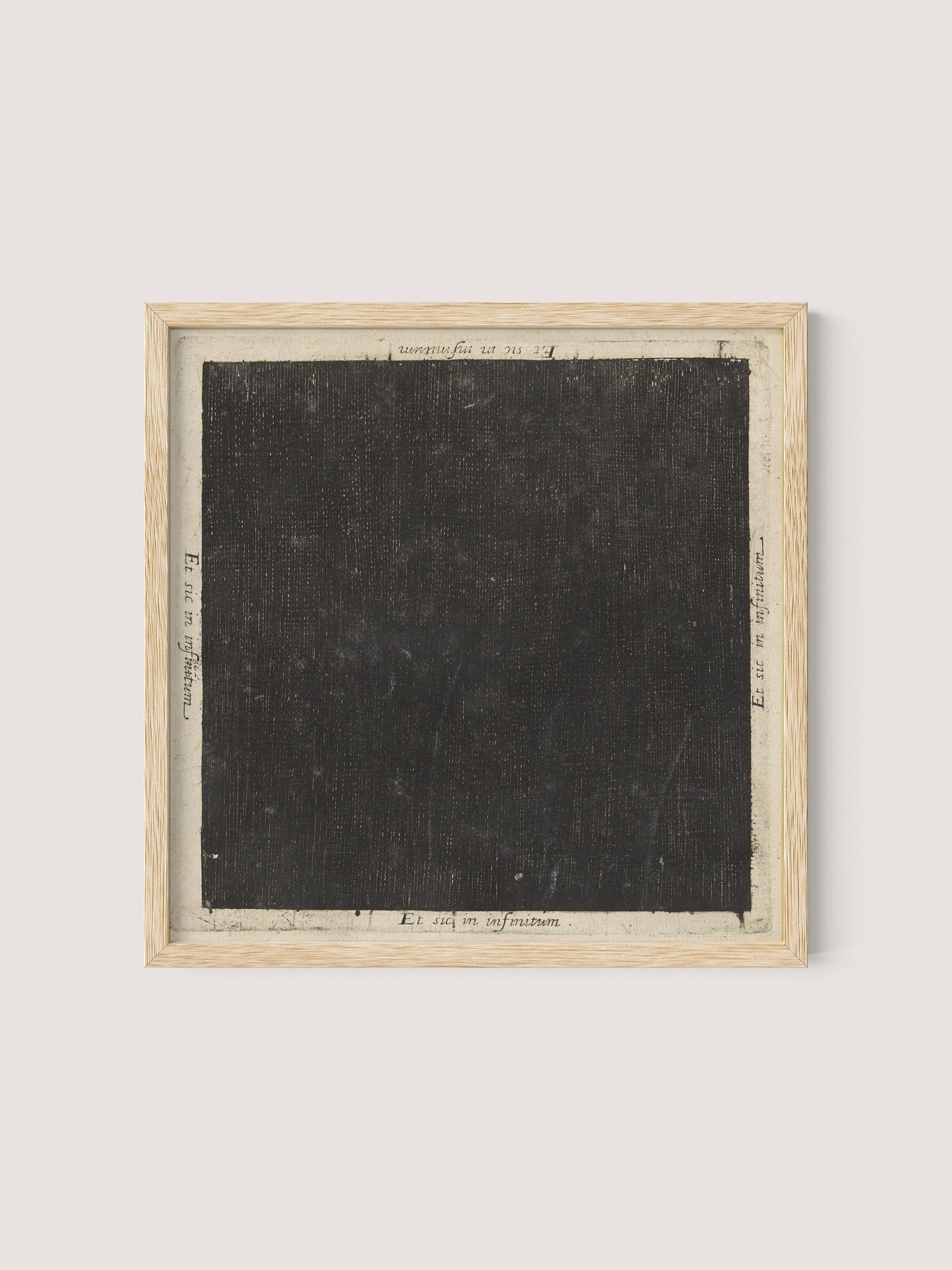 Introducing "Cosmic Square," a framed piece of art showcasing a large, textured black square perfectly centered on a white background. Reminiscent of a 17th-century etching, this artwork is encased in an elegant natural oak frame. Subtle handwritten text is discernible around the edges of the black square on the white backdrop.