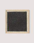 Introducing "Cosmic Square," a framed piece of art showcasing a large, textured black square perfectly centered on a white background. Reminiscent of a 17th-century etching, this artwork is encased in an elegant natural oak frame. Subtle handwritten text is discernible around the edges of the black square on the white backdrop.