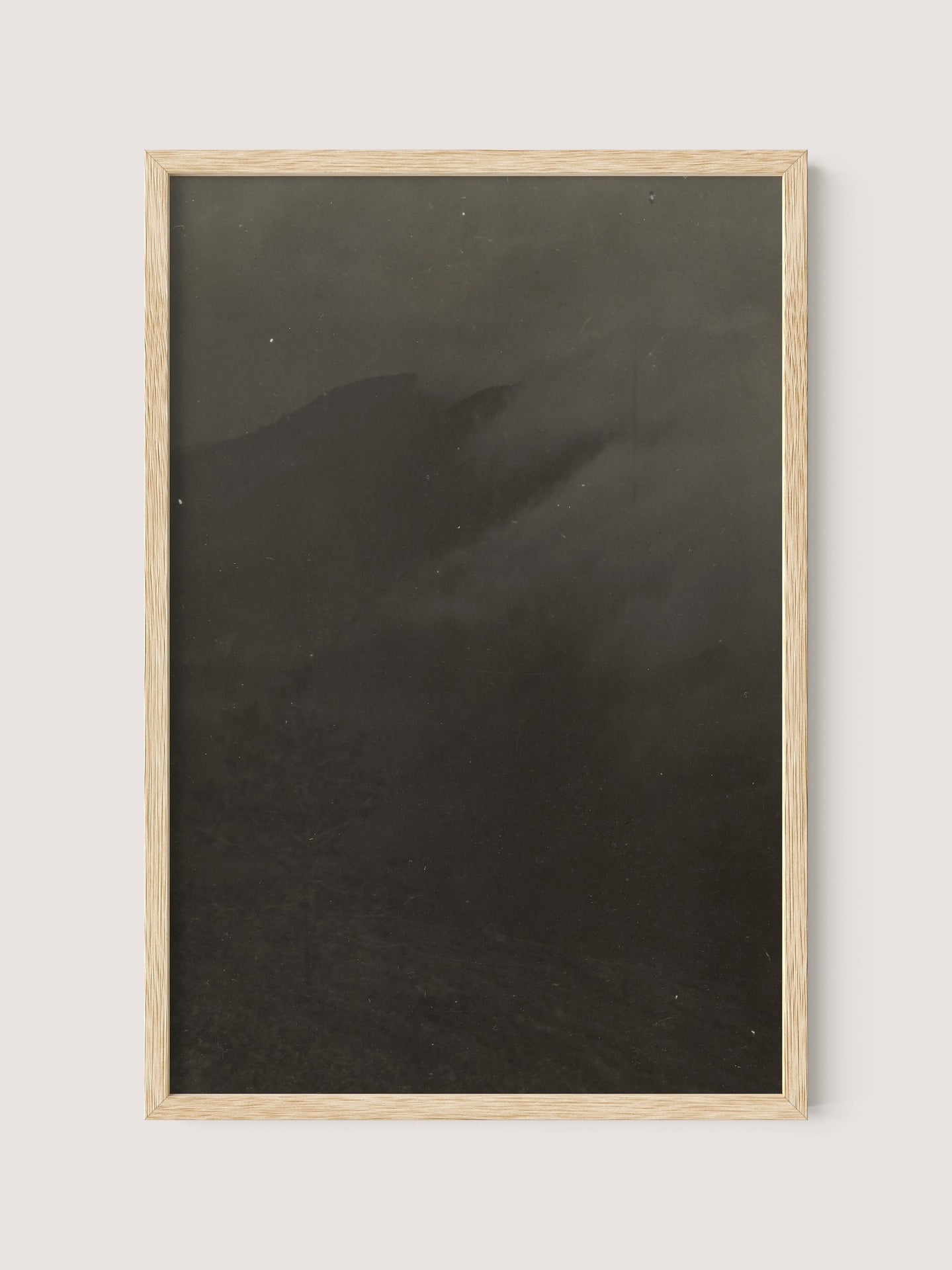 A framed print titled "Mountain Landscape," set in a natural oak frame, featuring a dark, monochromatic scene. The image is shadowy and vague, possibly depicting a misty or foggy mountainous area. This evocative piece might echo the work of 19th Century American photographer Louis Fleckenstein.