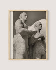 Framed black and white photograph titled "Olympic Men, Berlin," depicting two large Berlin Olympic statues standing close together. The statues are weathered and detailed against a backdrop of a partly cloudy sky. Captured by Paul Wolff during the 1936 Olympic Games, the frame is crafted from natural oak with a simple finish.