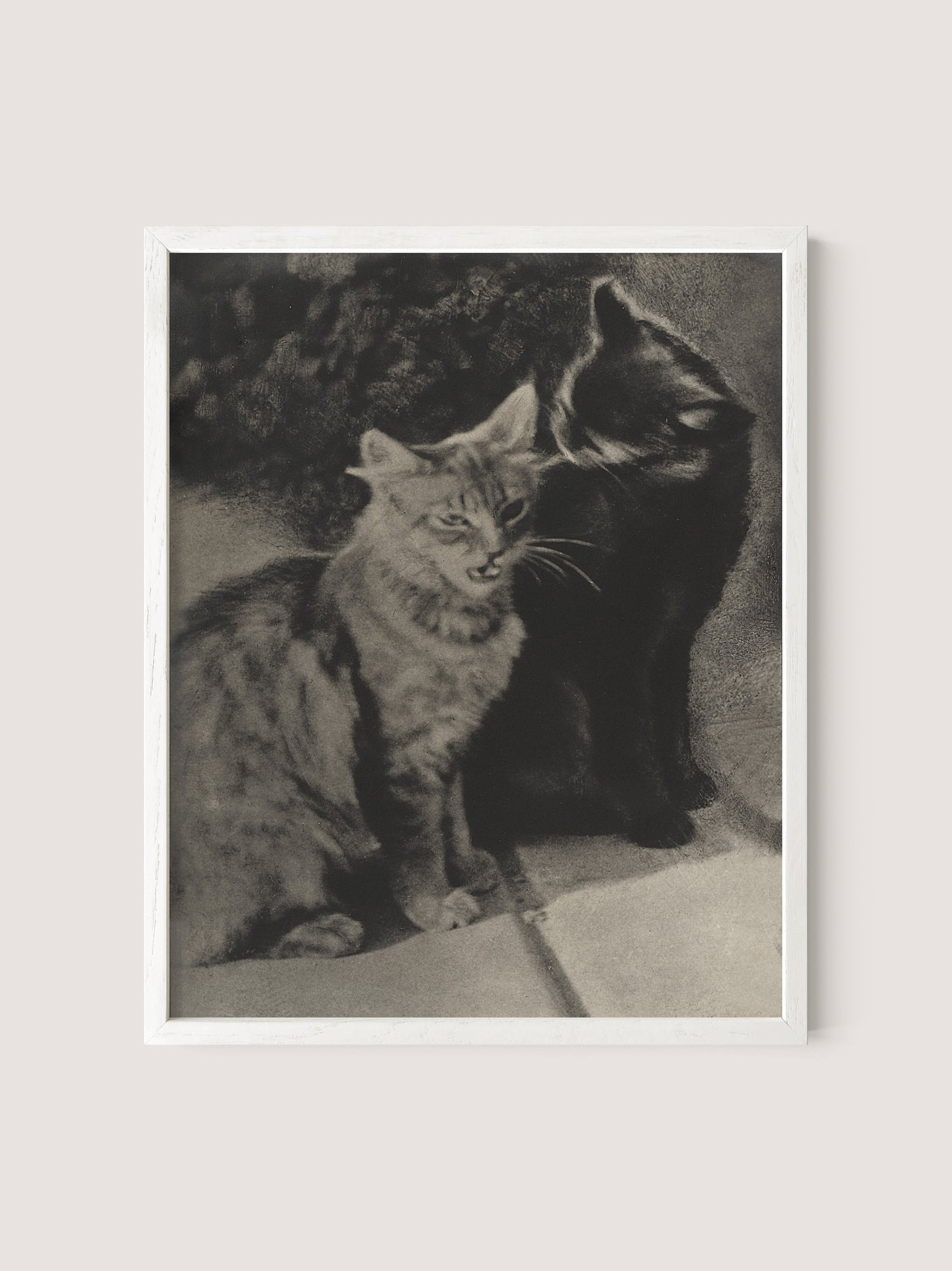 The Serenaders,&quot; a black and white print in a White Oak frame, depicts two feline friends. One dark-colored cat appears to be nuzzling or kissing the head of a lighter-colored, tabby cat. Both cats sit closely together on a tiled floor against a dark background.