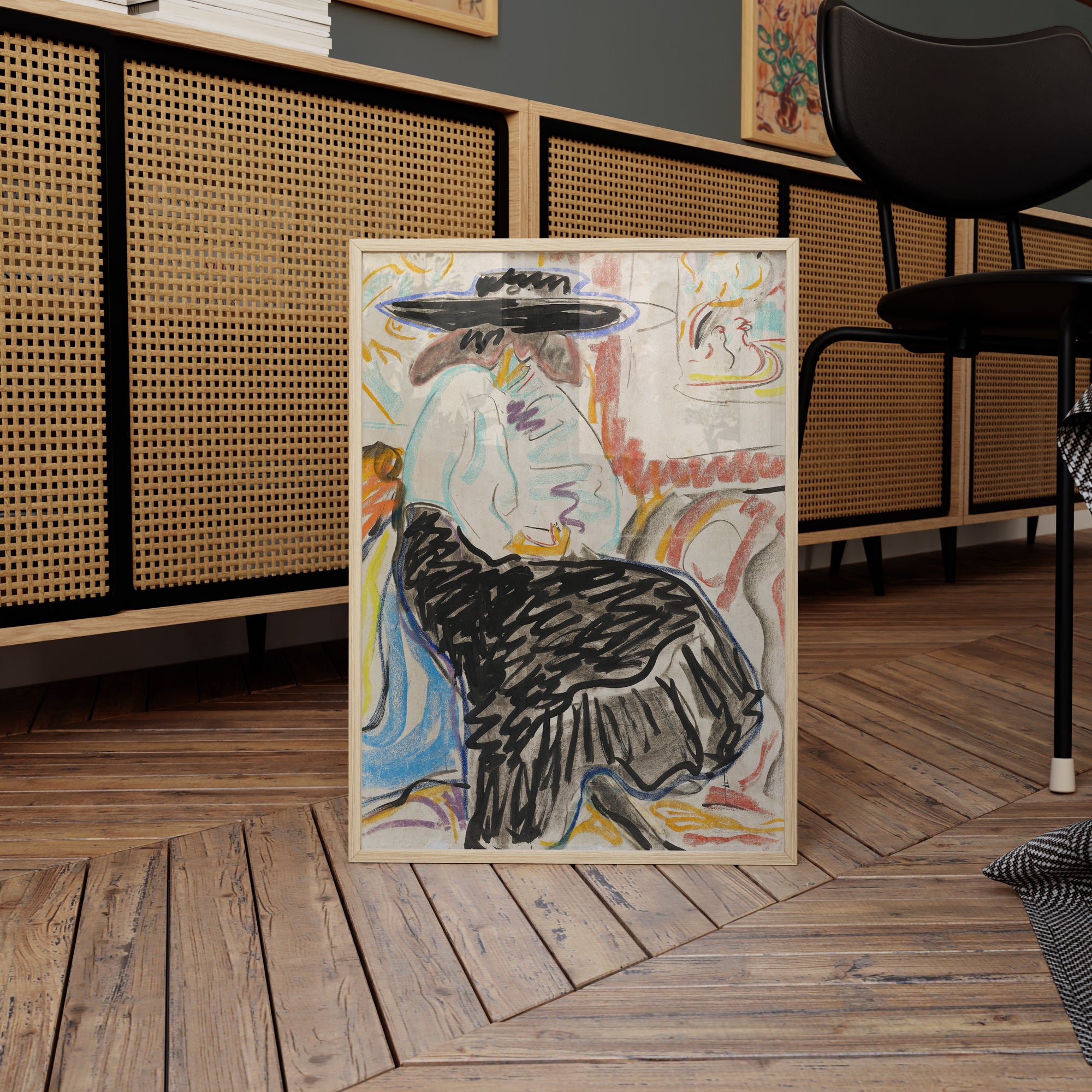 A framed abstract painting titled "Seated Woman in the Studio," evocative of figurative art, depicts a person in a black hat and white blouse. Displayed on a herringbone-patterned wooden floor, the background features a wicker-paneled cabinet and a black chair with a partial houndstooth cushion visible on the right, reminiscent of Kirchner's style.