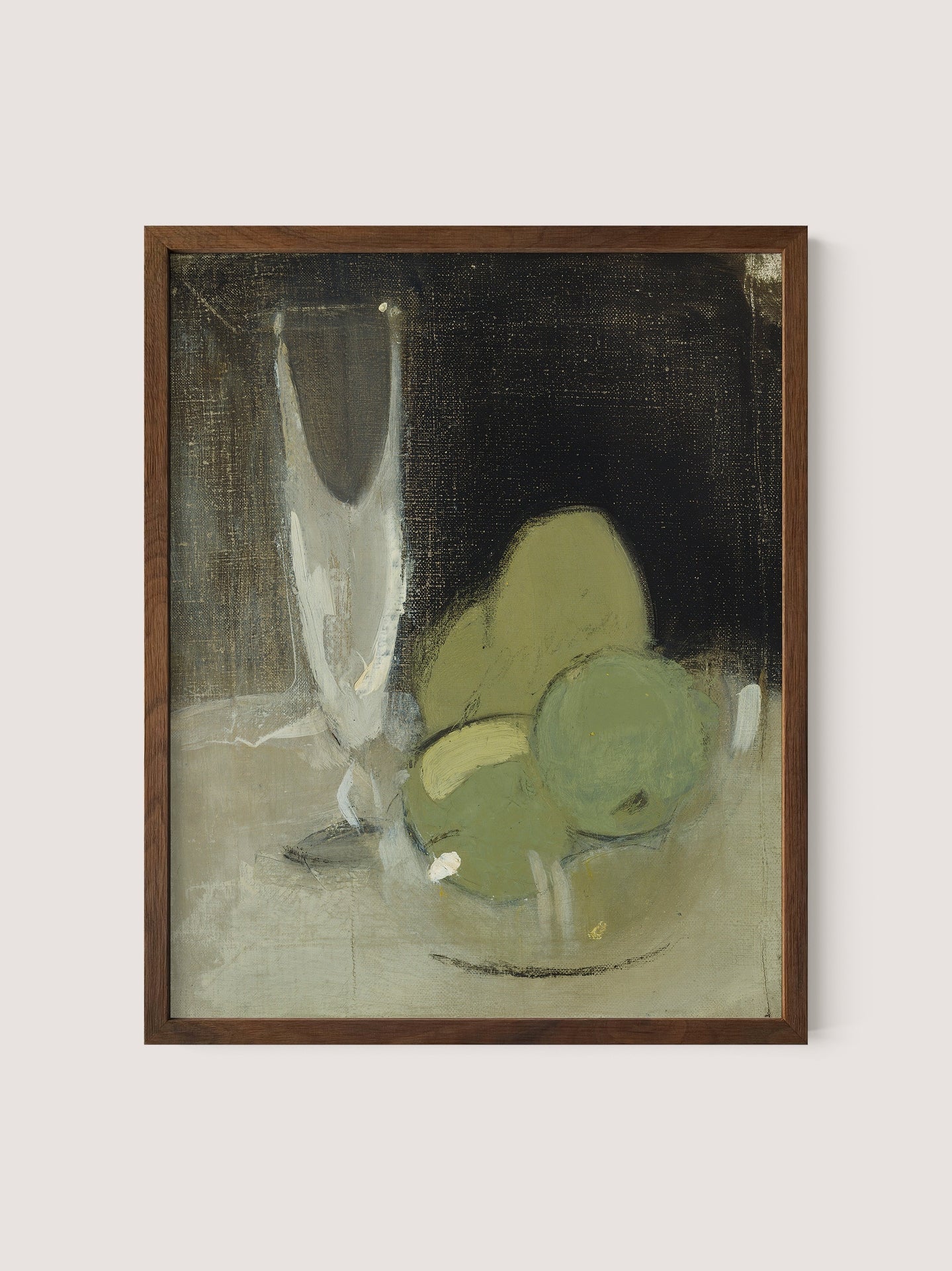 The framed piece titled &quot;Green Apples And Champagne Glass&quot; showcases a minimalist still life scene of a transparent glass and three green apples on a surface, set against a dark backdrop. The artwork exudes timeless elegance with its abstract style, muted earth tones, and soft brushstrokes in walnut oak hues.