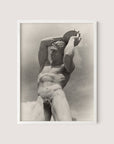 Black and white photograph of The Discus Thrower, a classical-style statue of a nude male figure holding a round object above his head. The statue appears muscular with detailed anatomical features. This Paul Wolff photo is framed in white oak and set against a pale background.