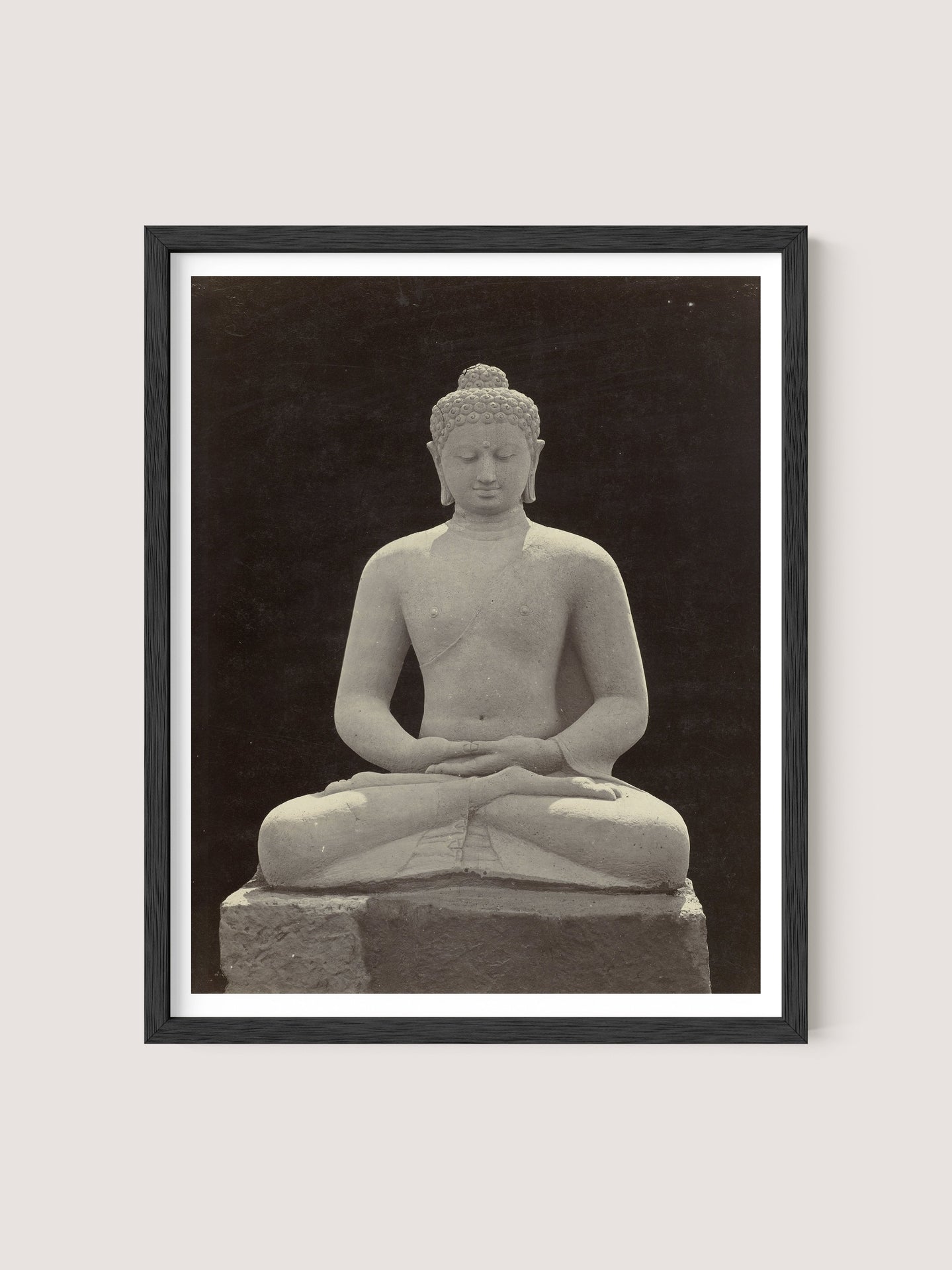 A framed photograph of a serene Buddha statue in a meditative pose, with legs crossed and hands resting on the lap. The Black Oak colored statue, reminiscent of those at Borobudur, is centered against a dark background, highlighting its calm expression and intricate details.