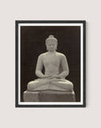 A framed photograph of a serene Buddha statue in a meditative pose, with legs crossed and hands resting on the lap. The Black Oak colored statue, reminiscent of those at Borobudur, is centered against a dark background, highlighting its calm expression and intricate details.