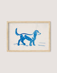 The framed painting, titled "Great Dane" by Peter Weisz Kubínčan, features a Great Dane walking against a white background. Illustrated with minimalistic brushstrokes, the dog stands on four legs and looks as if it is moving forward. The artwork, ideal for blue-toned decor schemes, is set in a natural oak wooden frame.