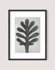 The "Yarrow Leaf" artwork features a simplistic and abstract depiction of a tree with thick, rounded, black branches extending upward. The light gray background enhances the modern minimalist style, while the sleek Black Oak frame adds to its botanical beauty.