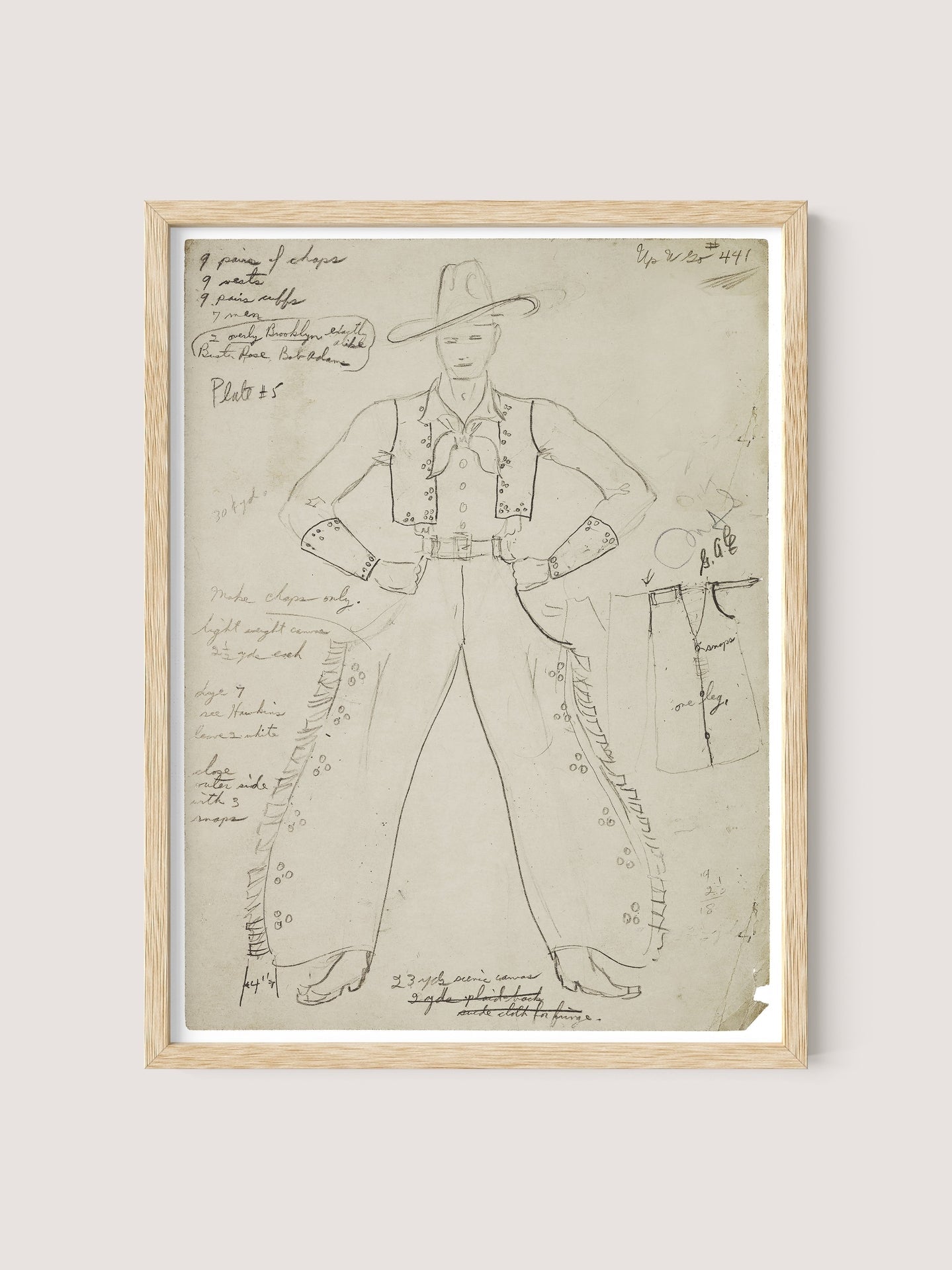 A framed sketch of the Cowboy Costume, featuring a hat, vest, and chaps. Detailed cursive annotations surround the figure, describing the design features and materials of the outfit. The sketch is reminiscent of pieces from the Federal Theatre Project era and is drawn on yellowed paper with a small tear in the bottom right corner. The frame is in a Natural Oak color.