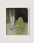 The "Green Apples And Champagne Glass" features a framed painting that depicts a still life with three greenish fruits in a glass bowl resting on a light-colored surface. A tall, transparent glass is positioned in the background against a dark backdrop, creating contrast with the muted earth tones of the objects and exuding timeless elegance. The frame itself is made from white oak, adding to its sophisticated appeal.