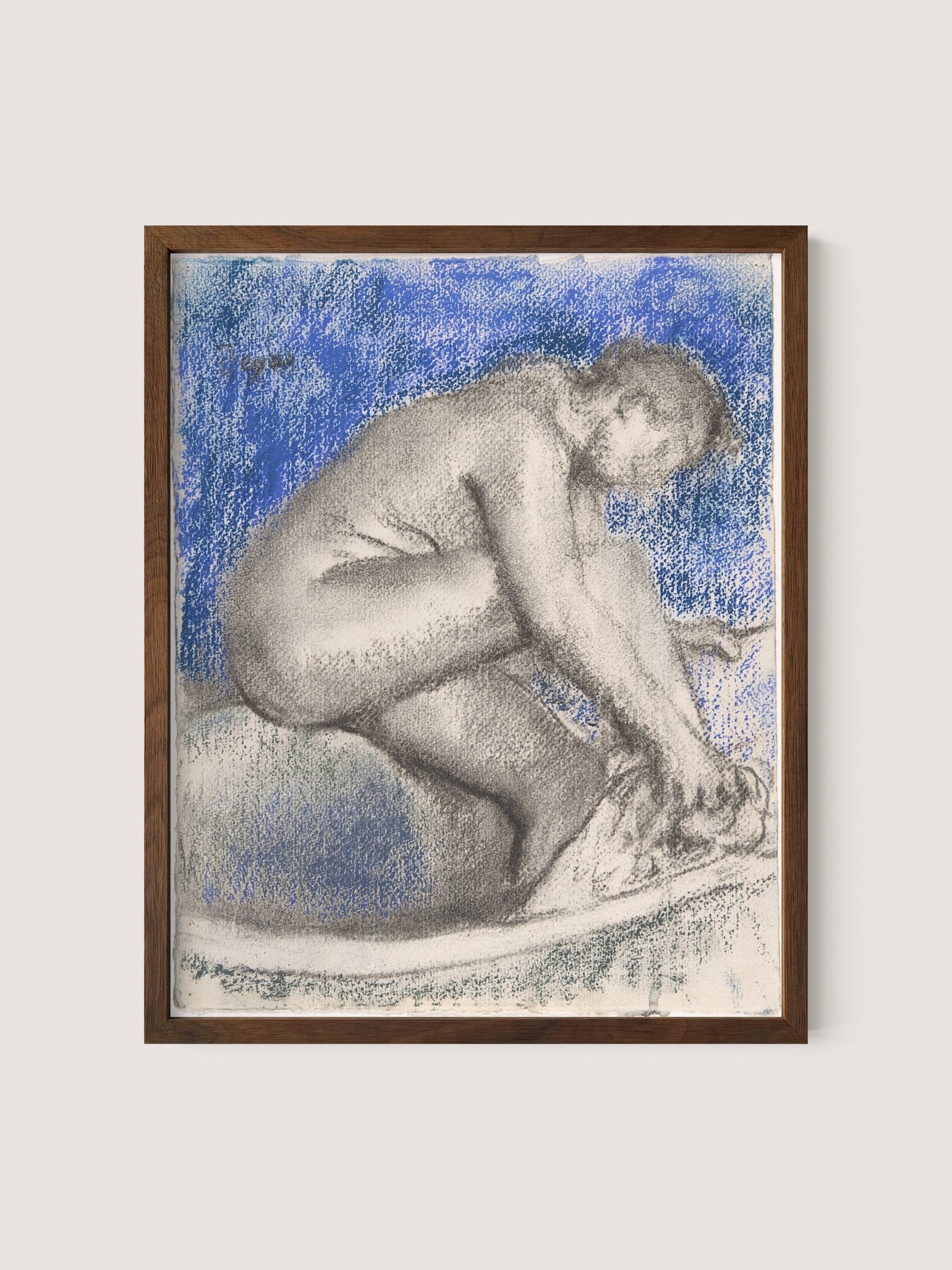 The Bath&quot; is a framed artwork of refined elegance depicting a nude figure crouched down, washing their feet. Rendered in charcoal or a similar medium, the piece features background shading in shades of blue, suggesting water or sky. This artwork exudes intimate introspection and is encased in a simple frame made of walnut oak.