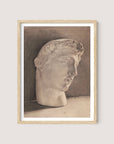 The "Study of a Plaster Head," framed in natural oak, portrays a neoclassical sculpture head rendered in sepia tone. The head is slightly oriented to the right, showcasing wavy hair and a contemplative expression. A minimalist gradient of brown shades in the background accentuates the piece's three-dimensional elegance.